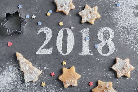 Christmas composition with raw cookies and figures 2018 made of flour on grey background