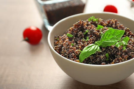 Bowl with boiled quinoa grains on wooden tableの写真素材