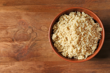 Bowl with boiled white quinoa grains on wooden tableの写真素材