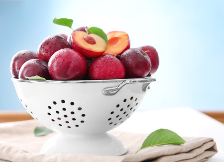 Collander with fresh ripe plums on tableの写真素材