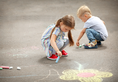 Cute little children drawing with chalk on asphaltの写真素材