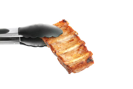 Tongs with delicious grilled ribs isolated on whiteの写真素材