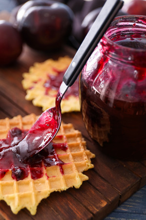 Spoon with tasty plum jam and wafer on tableの写真素材