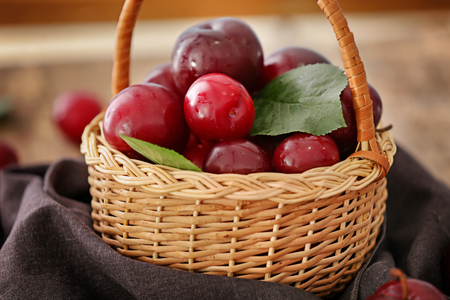 Wicker basket with ripe juicy plums on tableの写真素材