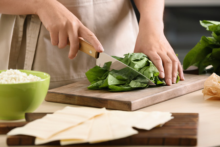 Woman cooking spinach lasagna in kitchenの写真素材