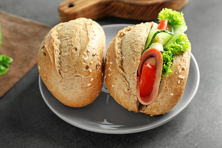 Tasty sandwich with fresh cucumber and bun on table
