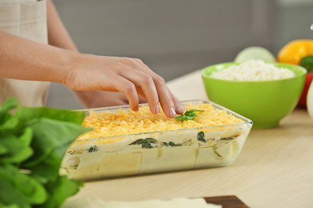 Woman cooking spinach lasagna in kitchenの写真素材