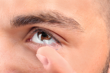 Young man putting contact lens, closeupの写真素材