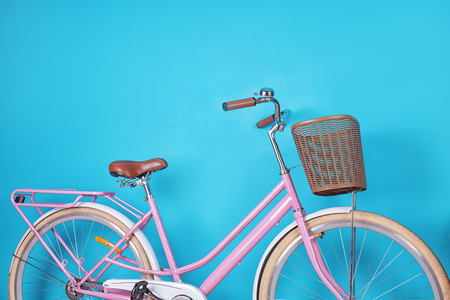 Modern bicycle with wicker basket on color backgroundの写真素材