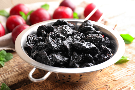 Collander with tasty dried plums on tableの写真素材