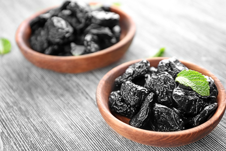 Bowls with tasty dried plums on tableの写真素材