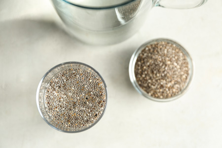 Glass of water and bowl with chia seeds on tableの写真素材