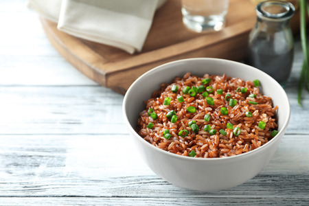 Bowl with tasty brown rice on wooden tableの写真素材