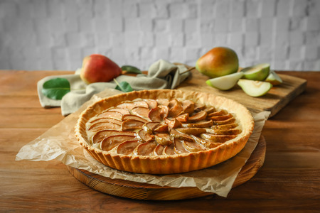 Wooden board with tasty pear tart on tableの写真素材