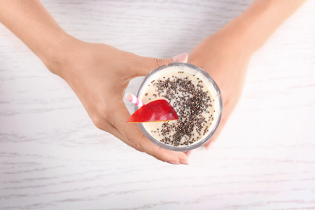 Female hands holding glass of smoothie with chia seeds on tableの写真素材