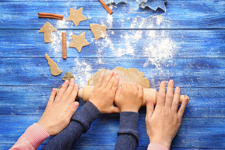 Young woman preparing Christmas cookies with little boy at tableの写真素材
