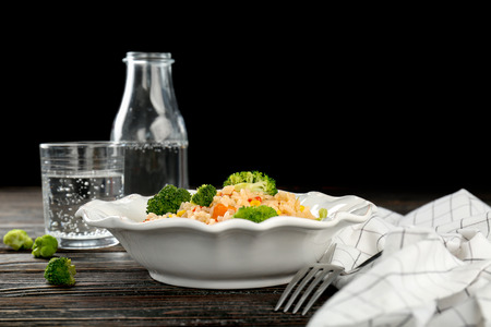 Plate with rice pilaf and broccoli on wooden tableの写真素材