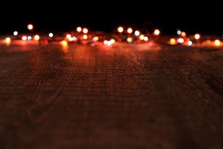 Christmas lights glowing on wooden table against black backgroundの写真素材