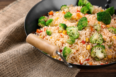 Delicious rice pilaf with broccoli in wok on wooden tableの写真素材