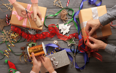 Family preparing decor for Christmas gifts on wooden backgroundの写真素材