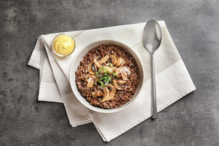 Bowl with delicious red rice and mushrooms on tableの写真素材