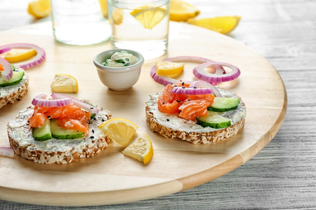 Tasty crispbreads with salmon on wooden boardの写真素材