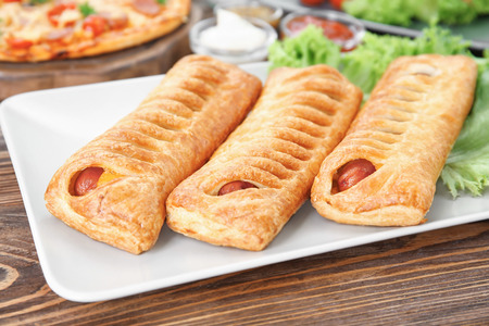 Plate with tasty sausage rolls on wooden tableの写真素材
