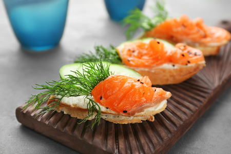 Board with tasty salmon bruschettas on table, closeupの写真素材