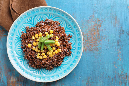 Plate with delicious red rice and vegetables on tableの写真素材