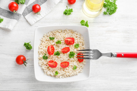 Plate with delicious brown rice and vegetables on tableの写真素材