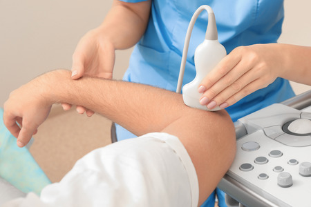 Doctor conducting ultrasound examination of patient's elbow in clinicの写真素材