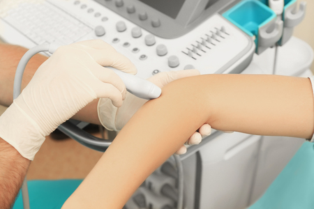 Doctor conducting ultrasound examination of patient's elbow in clinicの写真素材