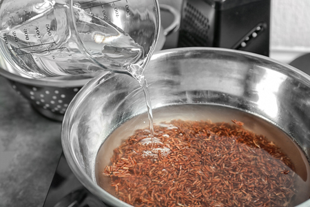 Pouring water into bowl with boiling riceの写真素材