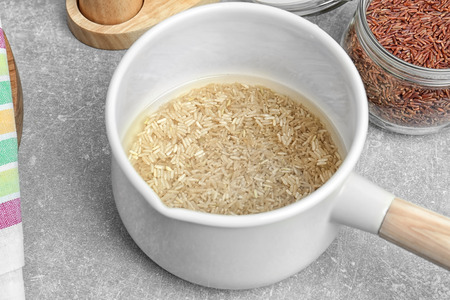 Washing raw rice in saucepan on kitchen tableの写真素材