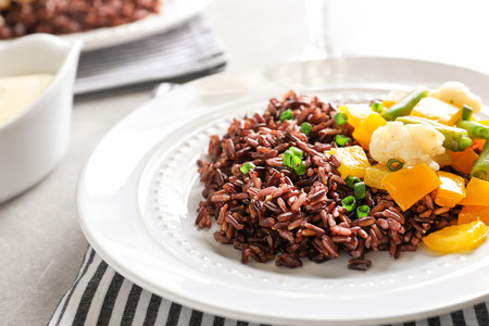Plate with delicious brown rice and vegetables on tableの写真素材
