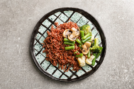 Plate with delicious brown rice and vegetables on light backgroundの写真素材