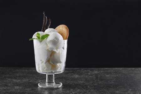 Glass with vanilla ice cream on table against dark backgroundの写真素材