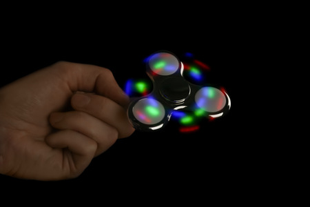 Man rolling modern luminous spinner on dark backgroundの写真素材