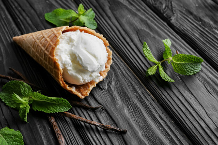 Waffle cone with vanilla ice cream on wooden tableの写真素材