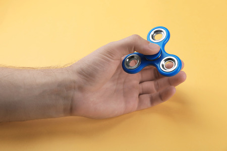 Man rolling modern spinner on color background