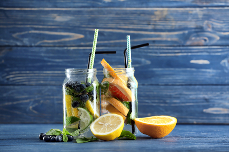 Mason jars of infused water with fruits on wooden tableの写真素材