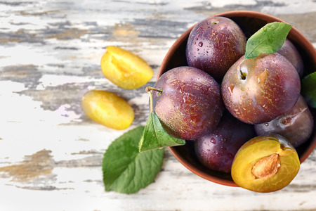 Bowl with ripe plums on tableの写真素材