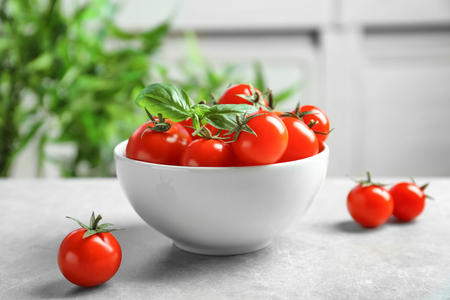 Ceramic bowl with ripe cherry tomatoes on tableの写真素材