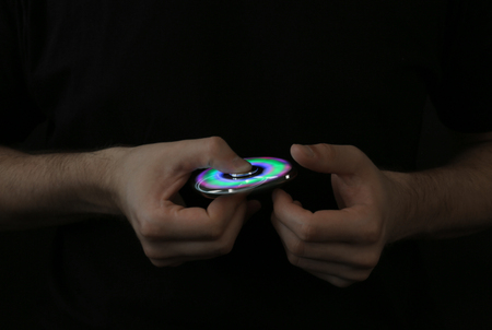Man rolling modern luminous spinner on dark backgroundの写真素材