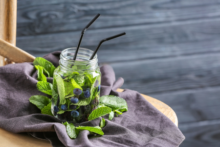 Jar of infused water with blueberry on chair against blurred wooden backgroundの写真素材