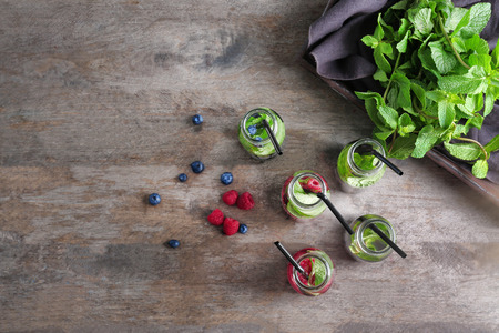 Bottles of infused water with berries on wooden tableの写真素材