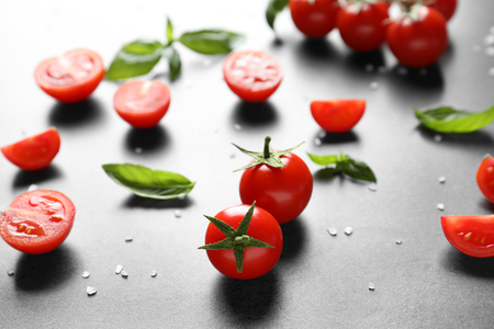 Fresh cherry tomatoes and basil on grey tableの写真素材