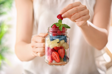 Woman holding mason jar with fruits and berries, closeupの写真素材
