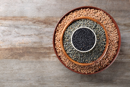 Bowls with different lentils on wooden tableの写真素材