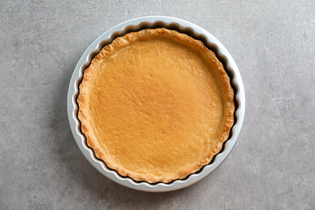 Crust for delicious cake in baking pan on table